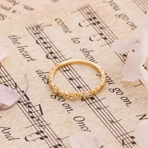 Macro di anello a foglia in oro 18K con zirconi su uno spartito musicale d'epoca