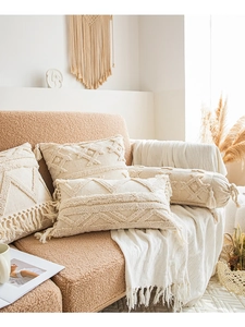 Detail of boho pillow covers featuring cream cotton fringe and tufted geometric patterns