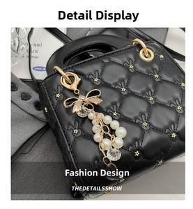 Detail of black quilted leather handbag with gold star studs and a pearl bow charm