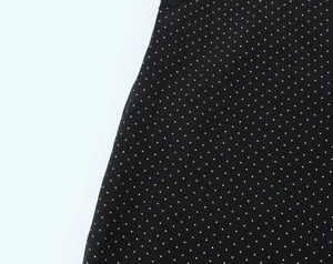 Detailopname van de zwarte stof met witte stippen en een gladde, lichte textuurafwerking