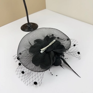 Detailed view of the black mesh veil with flocking dots and delicate feather accents