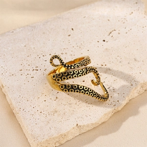 Classic punk octopus tentacle ring in gold finish on a textured travertine stone