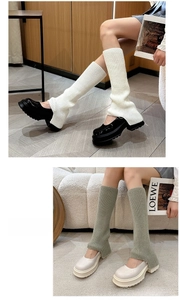 Close-up of cable knit leg warmers in white and sage green with vertical ribbed texture
