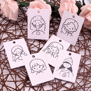Flat lay of cute cartoon girl earring display cards with roses on a textured mat