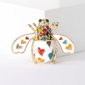 Detail of bee brooch with white enamel wings, colorful heart patterns and crystal accents