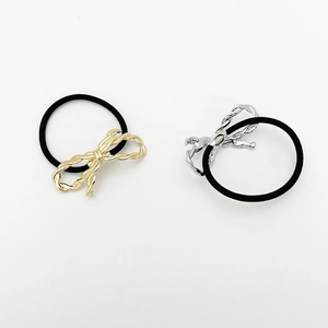 Close-up of black elastic hair ties featuring knotted gold and silver metal bow charms