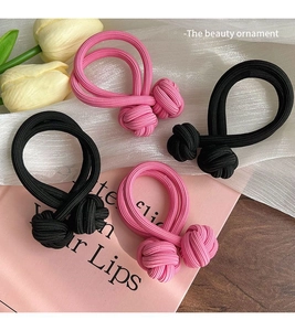 Détail d'élastiques à cheveux roses et noirs sur soie blanche avec fleurs