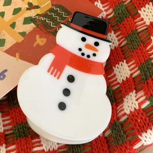 Macro shot of cute acrylic snowman hair clip with red scarf and hat on festive background