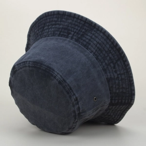 Détail d'un bob en jean délavé bleu marine avec œillets métalliques et surpiqûres