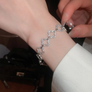 Detailed view of silver clover bracelet with pavé-set zircons on female wrist