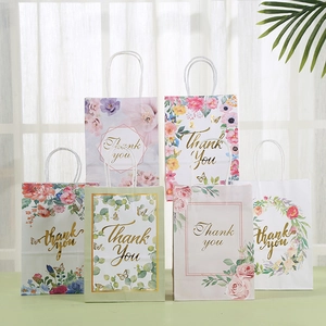 Detail of floral kraft paper gift bags featuring gold foil Thank You text and twisted handles