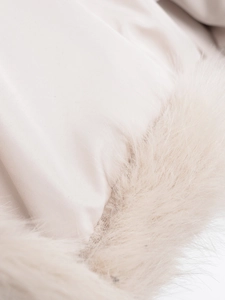 Gros plan sur la bordure en fausse fourrure et le tissu satiné du manteau beige