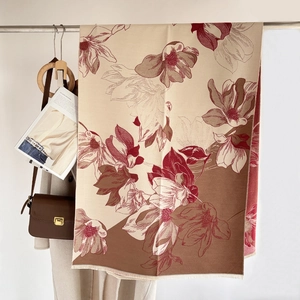 Detail of cashmere scarf featuring magnolia floral patterns and soft tassel edges