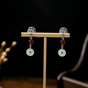 Detail of vintage Chinese earrings with red beads and light green stone rings on a stand