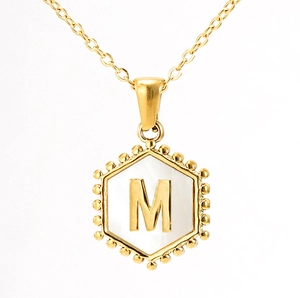 Detailed macro view of 18K gold hexagonal M letter pendant with white shell inlay