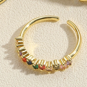 Macro detail of golden open ring with multi-color zircons and polished finish