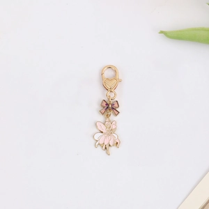 Detail of fairy keychain with pink bow and gold heart lobster clasp on white surface