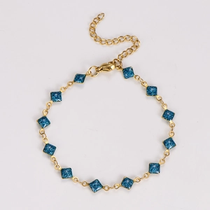 Detail of gold chain bracelet with blue glitter square charms and lobster clasp closure
