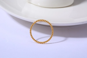 Detailaufnahme eines minimalistischen 18K vergoldeten Kordelrings auf Porzellan