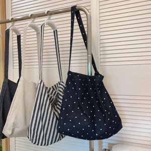 Selection of large canvas tote bags in polka dot, striped, and solid colors hanging together