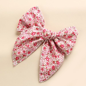 Detailed close-up of pink floral print fabric bow hair clip with fine edge stitching
