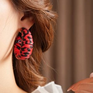 Close-up of model wearing C-shaped leopard print leather earrings in red and black
