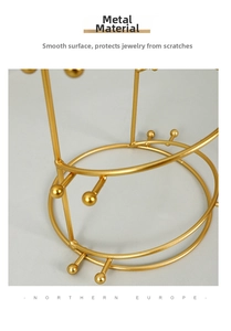 Detail of golden metal crown display stand with round hooks and smooth coating
