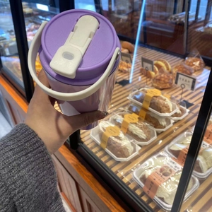 Close-up of purple insulated 30oz tumbler with ergonomic white handle in a cafe setting