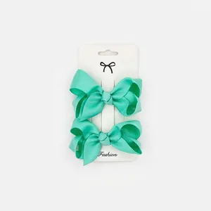 Detail view of mint green grosgrain ribbon bow clips on a white display card