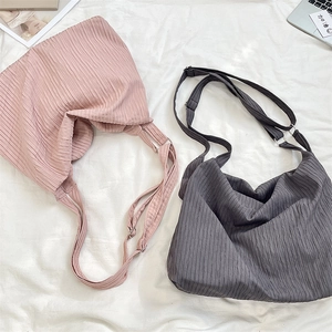 Detail view of pink and blue pleated canvas bags with adjustable straps in a lifestyle setting
