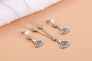 Macro shot of silver-colored fan-shaped necklace and earrings with Forever Love engraving