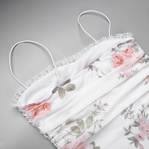 Detail eines weißen Camisole-Tops mit Blumendruck, Spitzensaum und rosa Rosenmuster