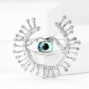 Macro shot of silver evil eye brooch with blue eye stone and sparkling rhinestones