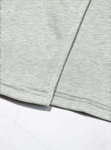 Detail of gray knitted fabric texture showing precise double-needle stitching on hem
