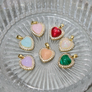 Close-up of colorful resin heart pendants with rhinestone edges in a textured glass bowl