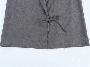 Detailed macro view of the grey blazer's fabric texture and stylish waist tie closure