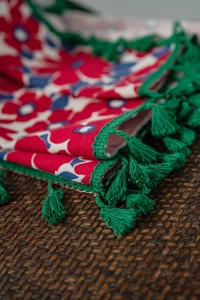 Close-up of red floral cotton linen fabric with green crochet lace and handmade tassels