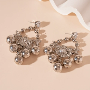 Détail de boucles d'oreilles argentées avec zircons floraux et boules en métal