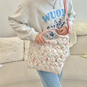 Detail of white quilted canvas bag with cartoon prints and pink braided handle