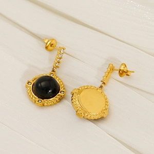 Boucles d'oreilles vintage en or 18k avec obsidienne et diamants sur tissu blanc