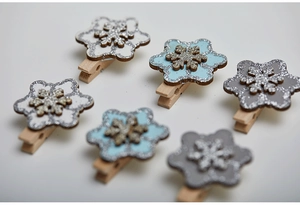 Macro detail of wooden snowflake clips with glitter finish in white, blue and grey colors
