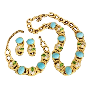 Vintage gold jewelry set with turquoise gemstones, pearls and crystals on a white background