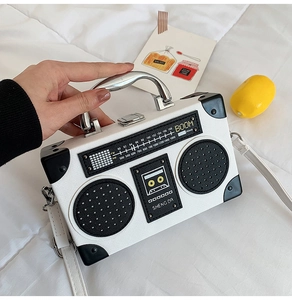Detail of white radio-shaped crossbody bag with silver handle and realistic dial print