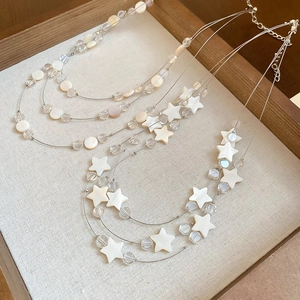 Détail d'un collier multicouche avec pendentifs étoile et coquillage en perles