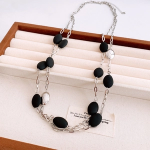 Close-up of double-layer silver chain with matte black oval beads on a display tray