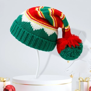 Festive red and green knit Christmas hat with pompom on white pedestal display