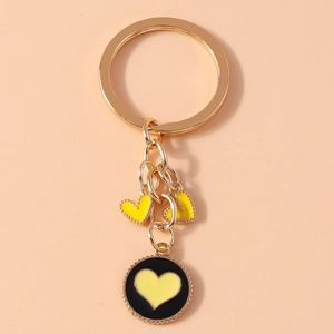 Close-up of golden metal keychain with yellow heart charms and black enamel pendant