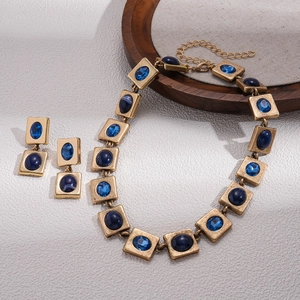 Vintage Gold Halskette und Ohrring Set mit blauen Schmucksteinen auf weißem Marmor