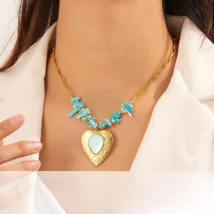 Detailed view of a gold heart pendant with blue stone on a gravel beaded chain