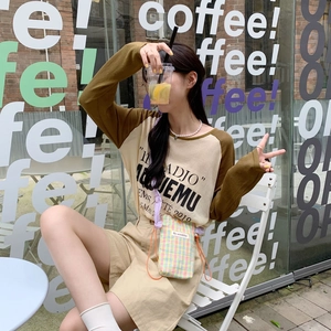Detail view of mini checkered crossbody bag with earth-toned casual outfit and street setting